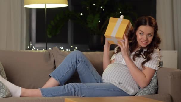 Feliz mujer embarazada sonriente con caja de regalo en casa — Vídeo de stock