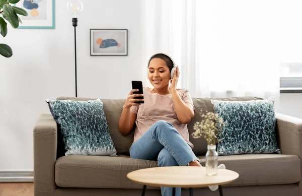 Mulher com smartphone ouvindo música em casa — Fotografia de Stock