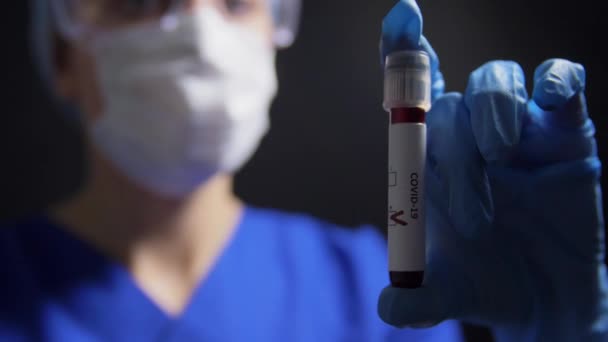 Médico sosteniendo vaso de precipitados con análisis de sangre de coronavirus — Vídeos de Stock