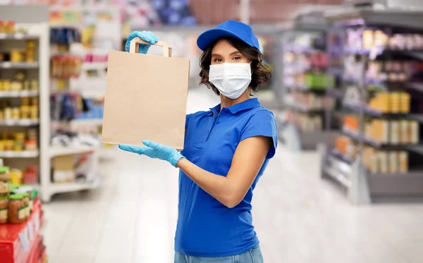 Femme de livraison en masque avec de la nourriture en sac en magasin — Photo