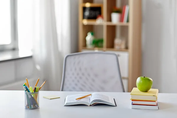 Книги, яблуко та шкільне приладдя на столі вдома — стокове фото