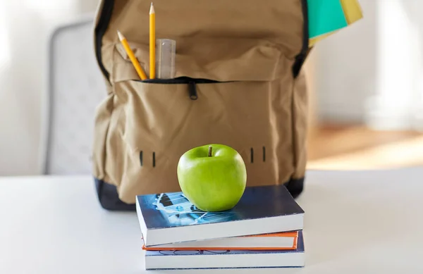 Σχολική τσάντα πλάτης με βιβλία και μήλο στο τραπέζι — Φωτογραφία Αρχείου