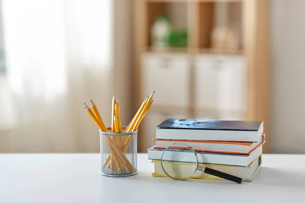 Könyv nagyítóval és ceruzával az asztalon otthon — Stock Fotó