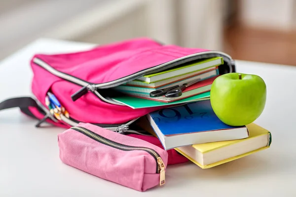 Mochila, manzana y útiles escolares en la mesa — Foto de Stock