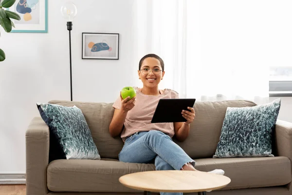 African woman with tablet pc and apple at home — Stock Photo, Image