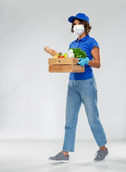 Mujer de entrega en mascarilla con comida en caja — Foto de Stock