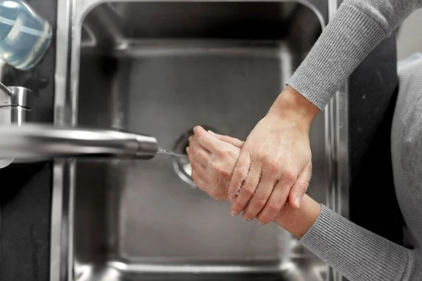 Mulher lavar as mãos com sabão líquido na cozinha — Fotografia de Stock