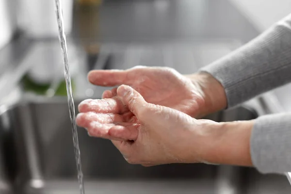 Женщина моет руки с мылом на кухне — стоковое фото