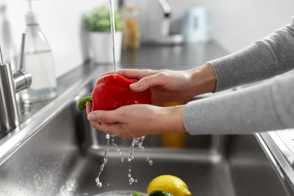 Kvinna tvätta frukt och grönsaker i köket — Stockfoto