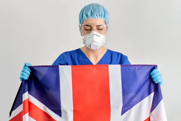 Orvos szemüveg és maszk gazdaság zászló Anglia — Stock Fotó