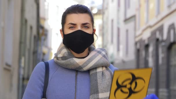 Frau mit Gesichtsmaske mit Biogefahrenschild in der Stadt — Stockvideo
