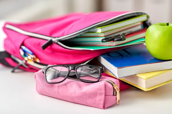 Mochila, manzana y útiles escolares en la mesa — Foto de Stock