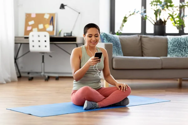 Žena se sluchátky a smartphone dělá sport — Stock fotografie