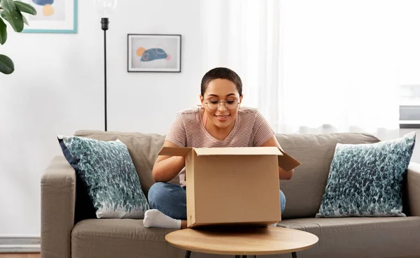 Mujer afroamericana abriendo caja de paquetes en casa — Foto de Stock