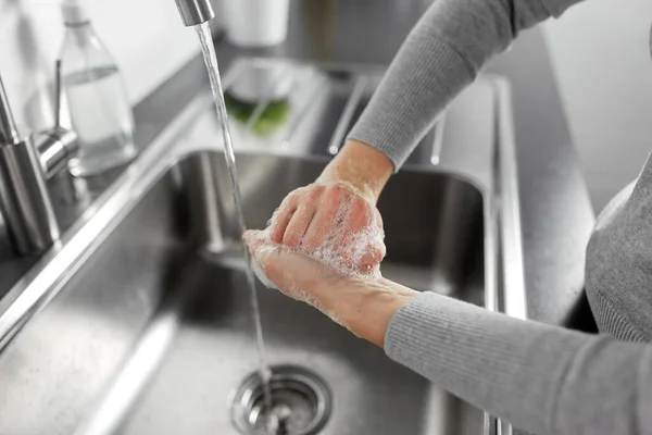 Woman washing hands with liquid soap in kitchen — Stock Photo, Image