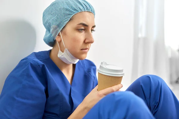 Trauriger Arzt oder Krankenschwester mit einer Tasse Kaffee zum Mitnehmen — Stockfoto