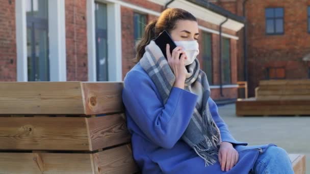 Vrouw in het gezicht masker bellen op smartphone in de stad — Stockvideo