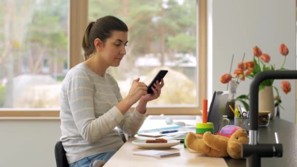 Jovem mulher com smartphone trabalhando no escritório em casa — Vídeo de Stock
