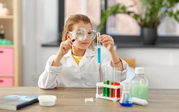 Chica con lupa y vaso de precipitados en el laboratorio de casa — Foto de Stock