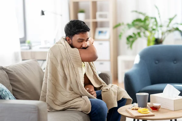 穿着毛毯在家里咳嗽的生病的年轻人 — 图库照片