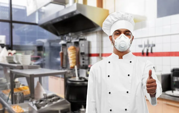 chef in respirator showing thumbs up at kitchen