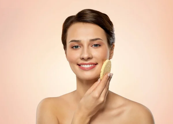 Young woman cleaning face with exfoliating sponge — Stock Photo, Image