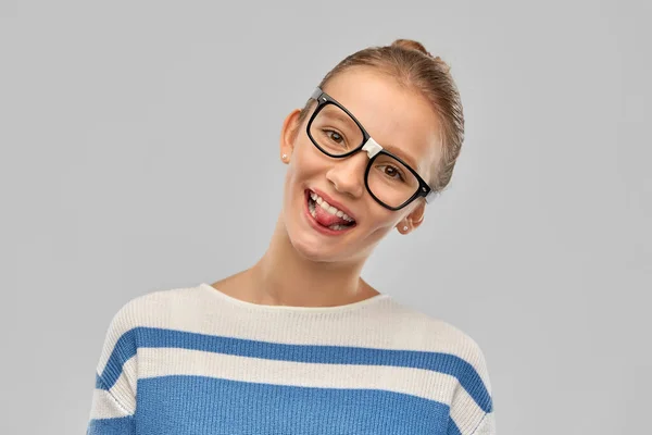 Adolescente estudiante chica en gafas mostrando lengua —  Fotos de Stock