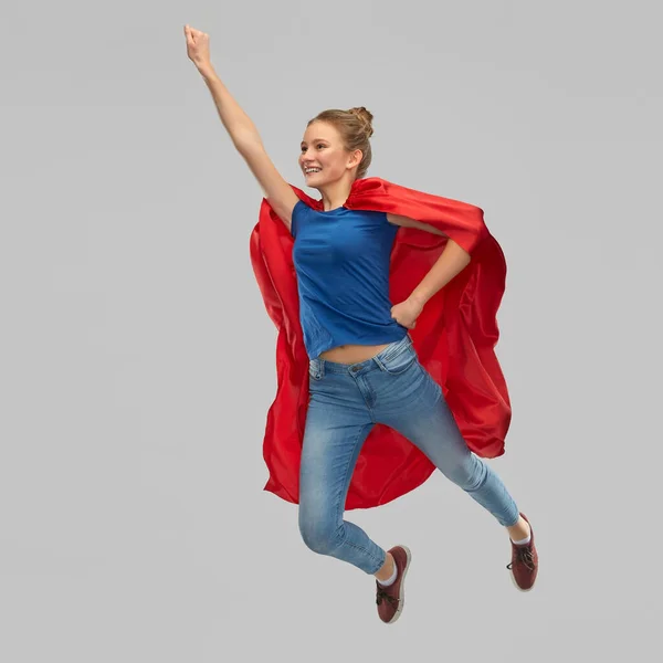 Sorridente adolescente menina em vermelho super herói capa saltando — Fotografia de Stock