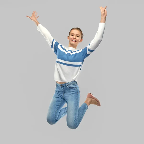 Улыбающаяся девушка-подросток в пуловере прыгает — стоковое фото