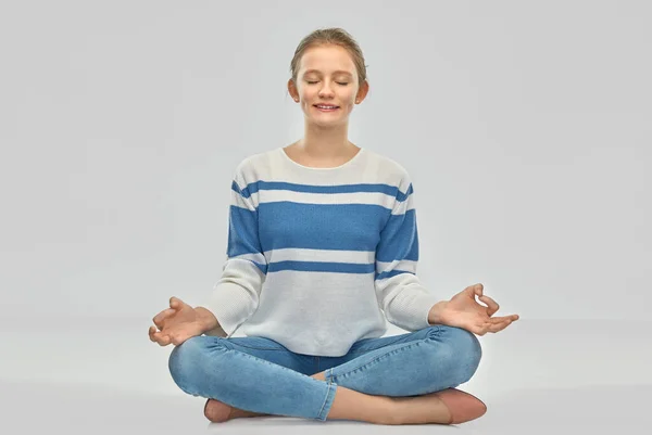 Улыбающаяся девочка-подросток медитирует в позе лотоса — стоковое фото