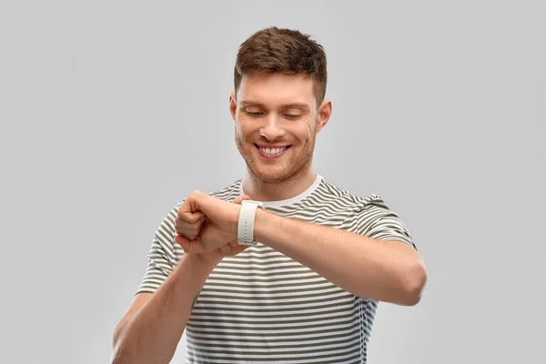 Lächelnder junger Mann mit Blick auf Smart Watch — Stockfoto