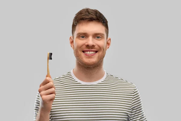 Улыбающийся мужчина с деревянной зубной щеткой — стоковое фото