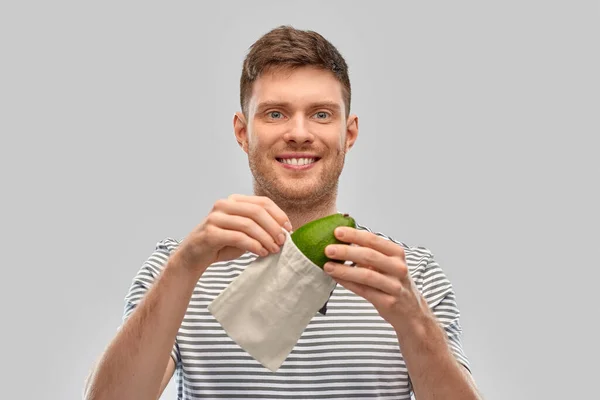 Usmívající se muž s avokádem v opakovaně použitelné plátěné tašce — Stock fotografie