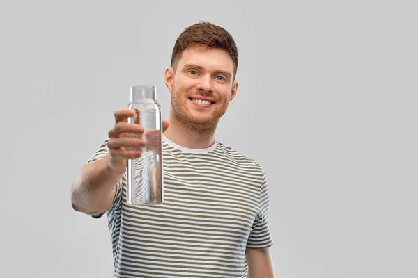 Feliz hombre sonriente sosteniendo el agua en botella de vidrio — Foto de Stock