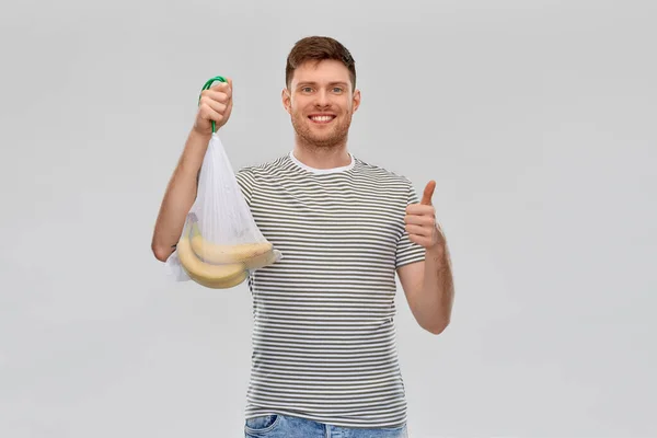 Homme heureux tenant sac à ficelle réutilisable avec des bananes — Photo