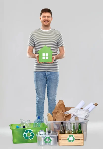 Улыбающийся молодой человек с отходами сортировки зеленых домов — стоковое фото