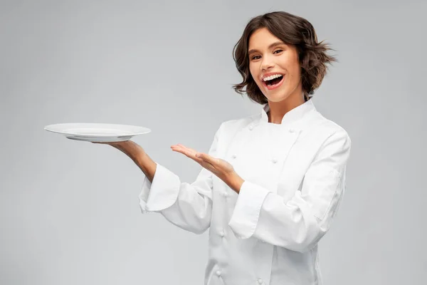 Chef sorridente femminile che tiene piatto vuoto — Foto Stock