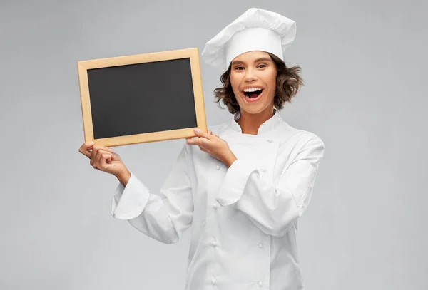 Uśmiechnięta kucharka trzymająca czarną tablicę — Zdjęcie stockowe