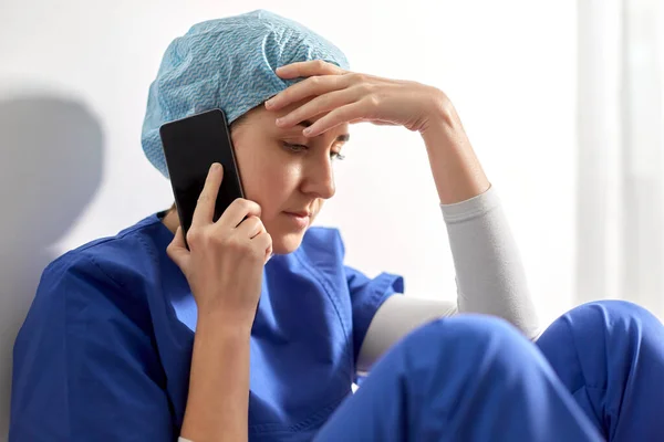 Triste médico o enfermera llamando en el teléfono inteligente —  Fotos de Stock