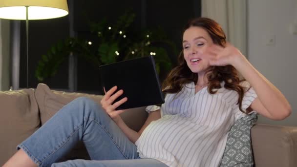 Счастливая беременная женщина с планшетным ПК дома — стоковое видео