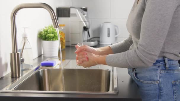 Женщина моет руки с жидким мылом на кухне — стоковое видео