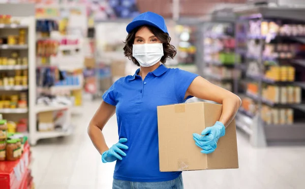 Delivery woman in face mask holding box at store — Stock Photo, Image
