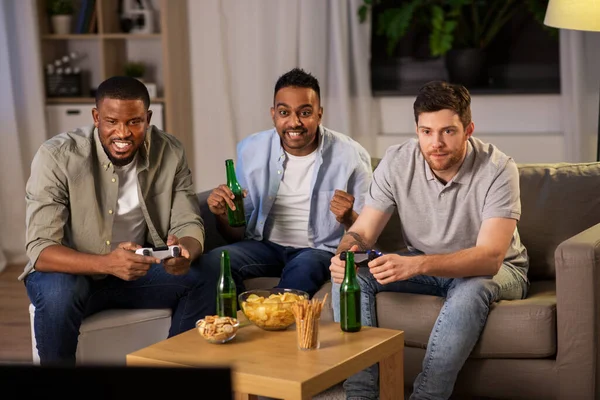 Amigos felizes jogando videogames em casa à noite — Fotografia de Stock