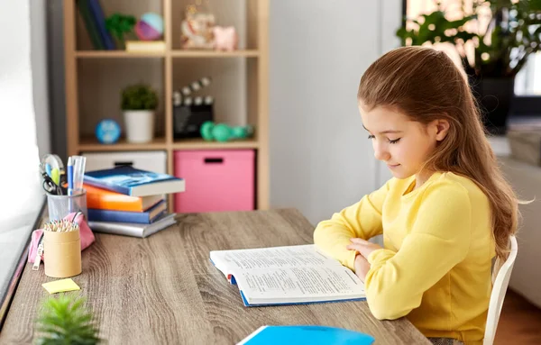 Liten student flicka läsa bok hemma — Stockfoto
