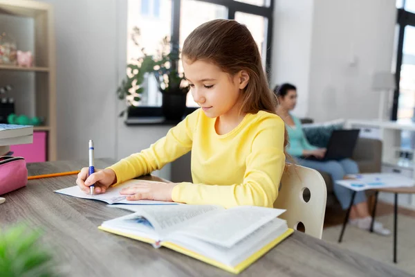 Student meisje met boek schrijven naar notebook thuis — Stockfoto