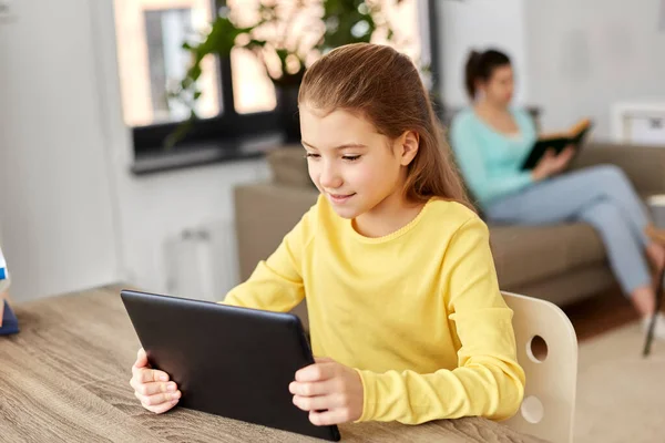 Estudante menina com tablet pc e mãe em casa — Fotografia de Stock