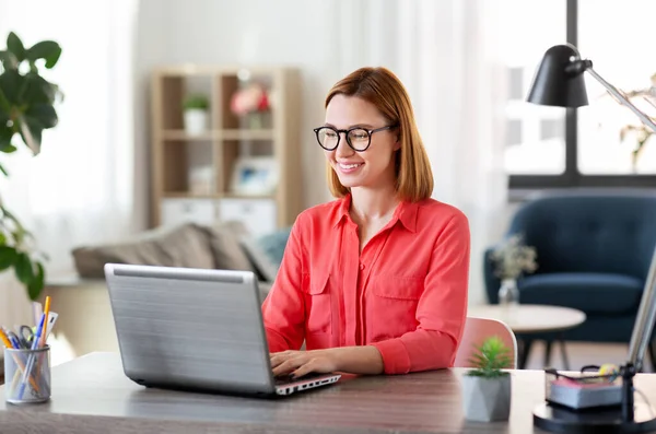 Femme heureuse avec ordinateur portable travaillant au bureau à la maison — Photo