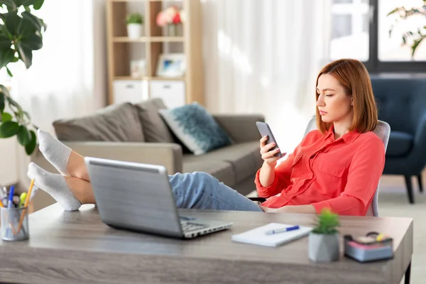 Frau mit Smartphone und Laptop im Home Office — Stockfoto