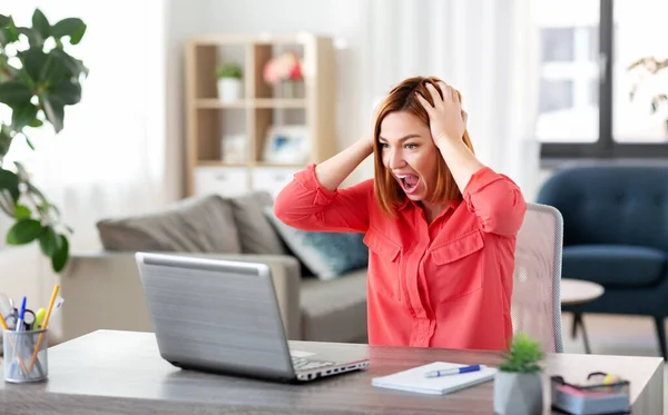 Сердитая женщина с ноутбуком работает в домашнем офисе — стоковое фото