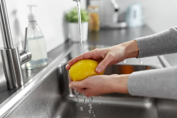 Närbild av kvinna tvätta citron frukt i köket — Stockfoto